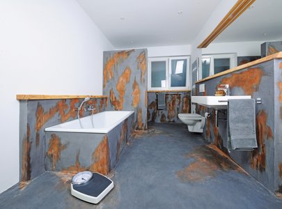Een van de badkamers valt op door zijn bijzondere ontwerp met rustieke vormgeving en kunstmatige roesteffecten.