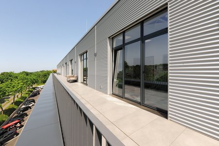 A roof terrace runs the length of the set-back upper floor, allowing employees to work outside or simply relax in their breaks.  Photo: Richard Brink GmbH & Co. KG