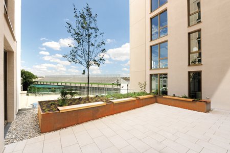 Op twee terrassen van het moderne kantoorcomplex werden verhoogde bedden van Richard Brink van cortenstaal geplaatst.