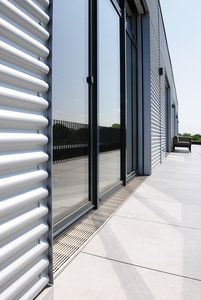Coiffés de grilles à tiges longitudinales de 7 x 7 mm en acier inoxydable, les caniveaux assurent une transition sans obstacle entre les bureaux et l’extérieur.  Photo : Richard Brink GmbH & Co. KG