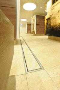 The stainless steel channels in the corridor of the changing rooms run along the entire length of the room. As they were made to measure, the channels fit in aesthetically with the tile grid.