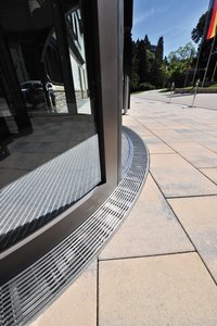 Custom-made radial Cubo channels frame the revolving door in the entrance hall and are fitted with Hydra Linearis gratings. They are both aesthetically pleasing and also practical – the perfect dewatering solution. 