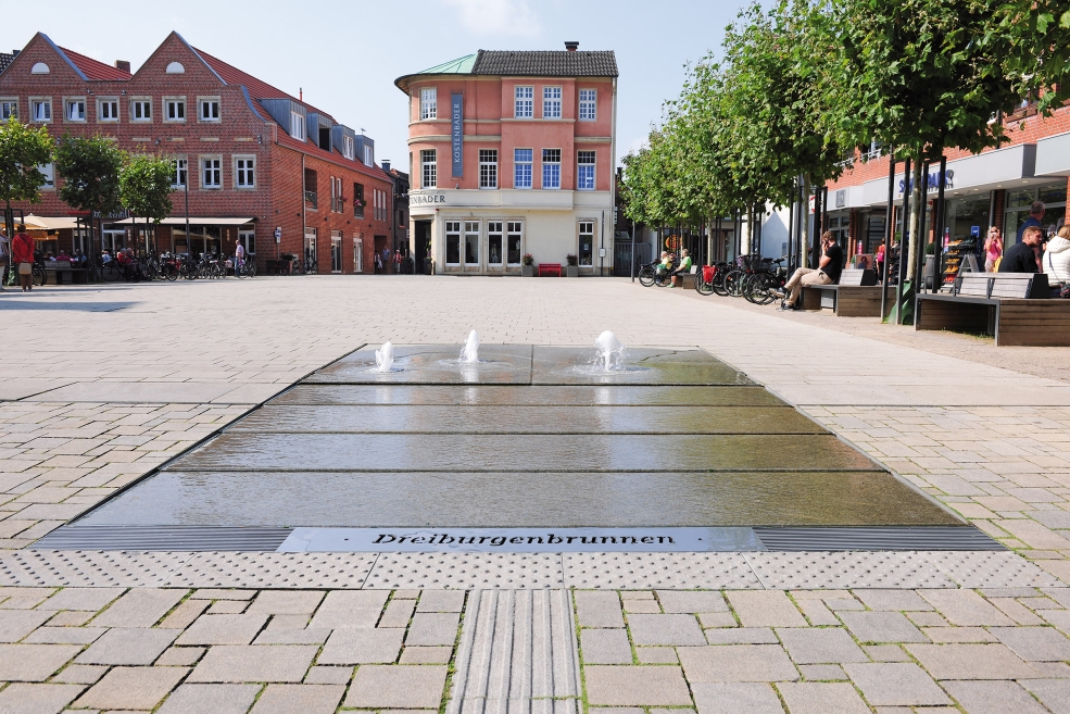 [Translate to Französisch:] Am Marktplatz in Lüdinghausen ist eine ebenerdige Brunnenanlage entstanden, die symbolisch der eigenen Stadtgeschichte und hiesiger Sehenswürdigkeiten Rechnung trägt.