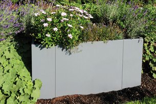 Modularer Pflanzkasten in grau im grünen Garten bepflanzt
