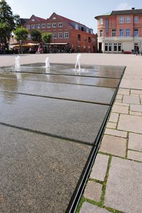 Custom heavy-duty slotted channels from Richard Brink run around the feature and ensure that the water keeps circulating. They match the gradient of the slabs precisely and form a streamlined transition between the water feature and the rest of the square.