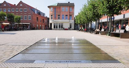 Am Marktplatz in Lüdinghausen ist eine ebenerdige Brunnenanlage entstanden, die symbolisch der eigenen Stadtgeschichte und hiesiger Sehenswürdigkeiten Rechnung trägt.