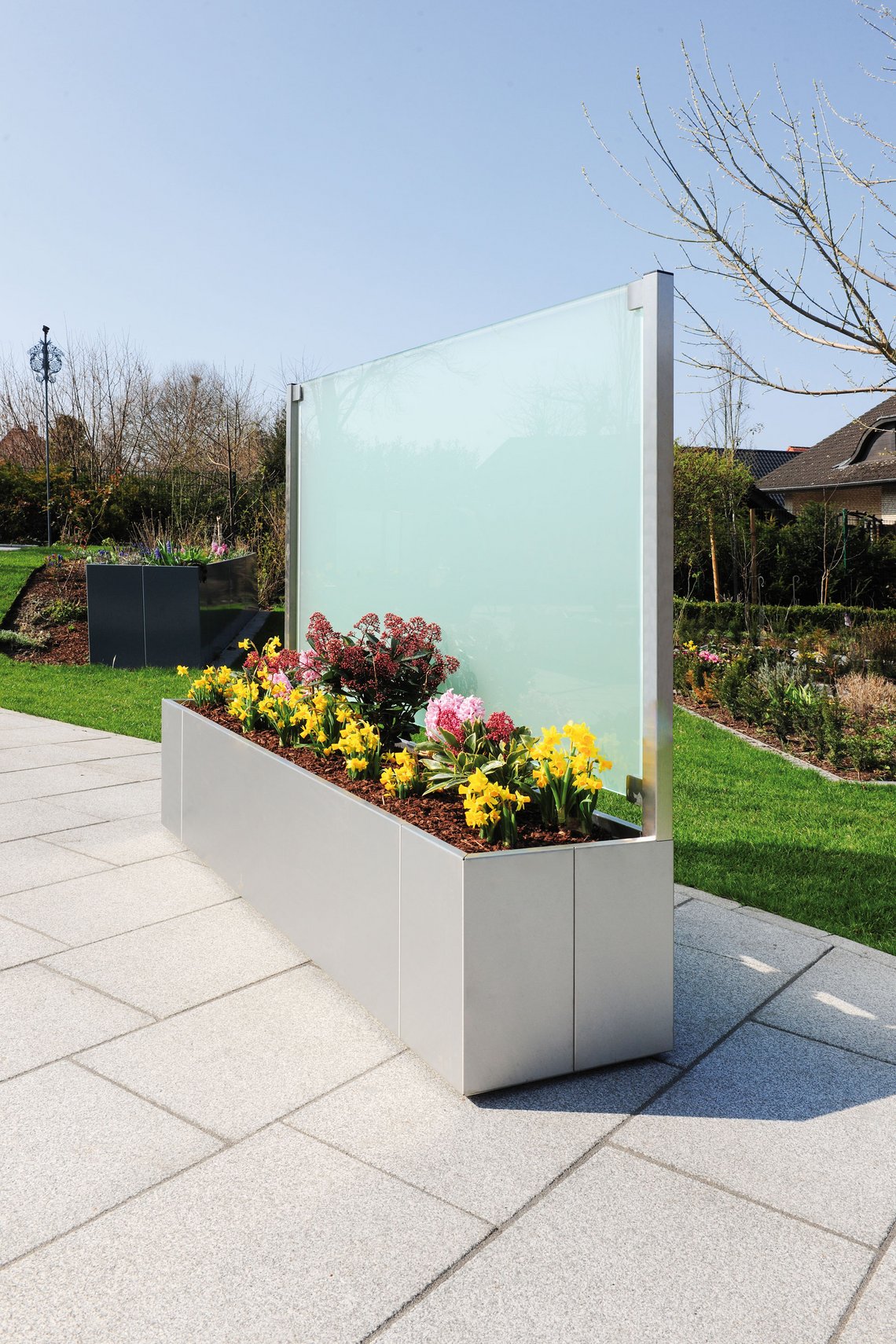 Metall Pflanzkasten aus Edelstahl mit satiniertem Glas als Rückwand auf der Terrasse im Garten