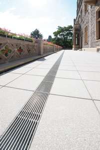 Les caniveaux de drainage en acier galvanisé longent la balustrade sur toute sa longueur en recouvrant des évacuations posées à distance régulière.