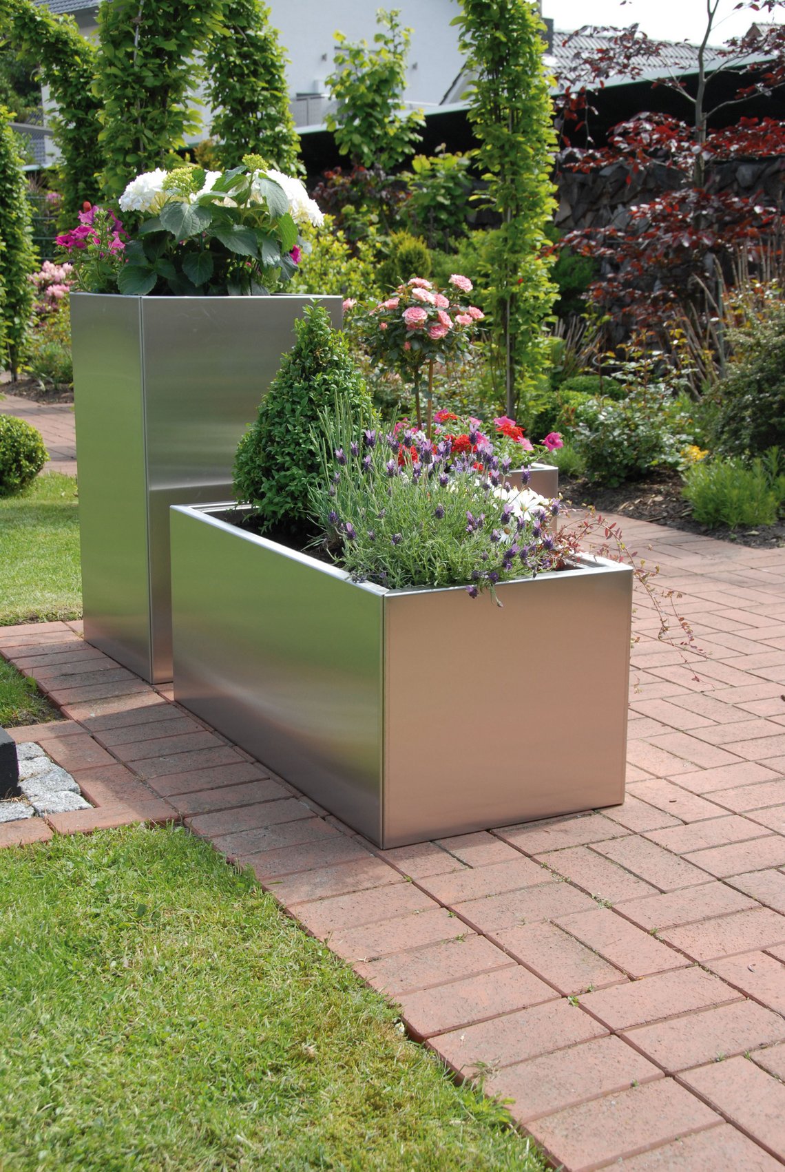 Pflanzkästen mit Pflanztrog aus Edelstahl mit blühenden Pflanzen auf der Terrasse im Garten