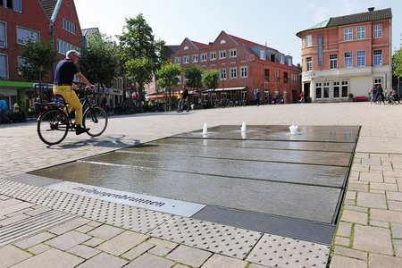 The large-format natural stone slabs of the water feature are slightly graded to achieve a gradient for the water to drain. The area is still completely barrier-free, however, and can even be crossed by cyclists.