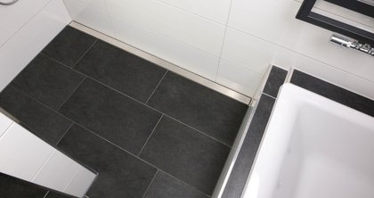 Timeless and practical – the main upstairs bathroom of this home in Schloß Holte-Stukenbrock is finished in white and anthracite. The shower channel cover from the company Richard Brink creates an exciting contrast to the tiles. 