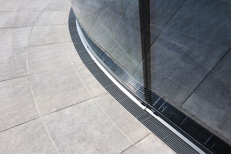 Cubo Radial permet à la ligne de caniveaux de s’adapter idéalement à la façade. Les produits de l’entreprise Richard Brink accompagnent ainsi la forme donnée au hall d’exposition qu’ils protègent de l’extérieur.