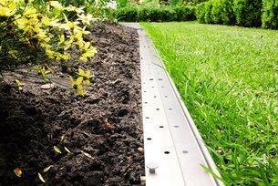Gerade Rasenkante aus Metall von Richard Brink trennt ein Beet vom grünen Gras