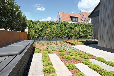 Den Bodenbelag der neu gestalteten Fläche prägen helle, längliche Natursteinplatten, die auch innerhalb der Beete ein Durchschreiten ermöglichen. Sie bilden gewissermaßen zwei Zebrastreifen, die zudem die Pflege der Beetflächen durch eine bessere Zugänglichkeit erleichtern.  Foto: Richard Brink GmbH & Co. KG
