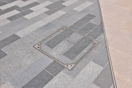 Thanks to the integrated paving tray, the covers blend into their surroundings and achieve a uniform overall look. The metal edging of the frame and cover creates an effective contrast with the surrounding slab material.