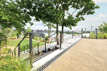 Die 80 mm hohen Rinnen der Richard Brink GmbH & Co. KG aus Beton unterstreichen in Kombination mit den Gussrosten „Zippa“ auch das Farbkonzept, geprägt durch dunkle Geländer und Streifen entlang der Treppen.  Foto: Richard Brink GmbH & Co. KG