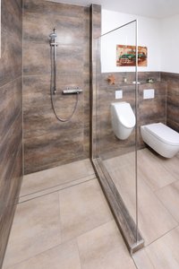 The guest bathroom on the ground floor of the detached family home has a sophisticated, purist style. The floor boasts a harmonious look thanks to the installed tiled tray.