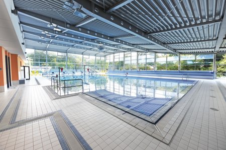 Het rolstoelvriendelijk ontworpen overdekte zwembad omvat een groot wedstrijdbad en een leszwembad met verstelbare bodem.