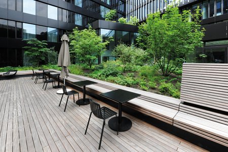 Integrierte Sitzgelegenheiten aus Holz bieten Möglichkeiten zum Verweilen oder Arbeiten im Außenbereich. Sie gehen optisch nahtlos in den Bodenbelag der Terrassenfläche über.