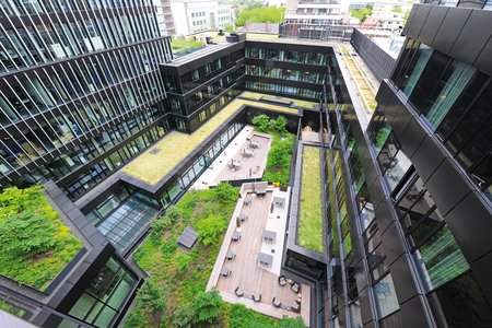 Meerdere kubistische gebouwdelen vormen samen niveaus rondom een groene binnenplaats.