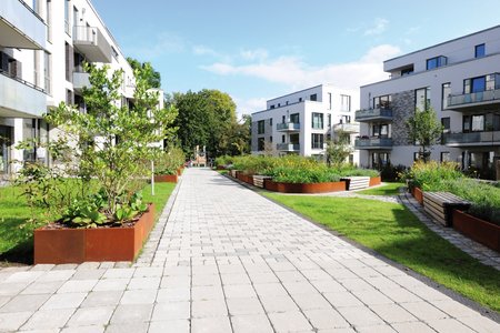 Grâce au matériau choisi, les jardinières hautes créent des contrastes forts avec la couleur claire des sols pavés et des façades.