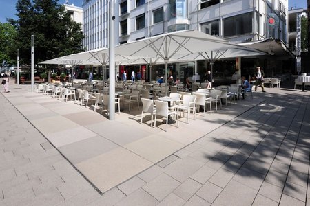 Großformatige Betonplatten in Rosé, Ocker und Sandfarben komplettieren das Farbschema des Pflasters am Marktplatz und trennen Bereiche für Einzelhandel oder Gastronomie von der Fußgängerzone ab.