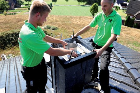 The roofers place an expansion joint flashing in the flue of the chimney that prevents the concrete from flowing into the flue. At the same time, they pull the wall anchors in the cladding upwards to make sure they will be securely embedded in the concrete. 