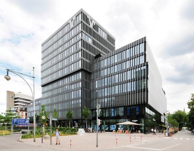 The striking façade features floor-to-ceiling windows set behind a curtain-wall lamellar structure, which appears to hover in front of the building’s outer shell.