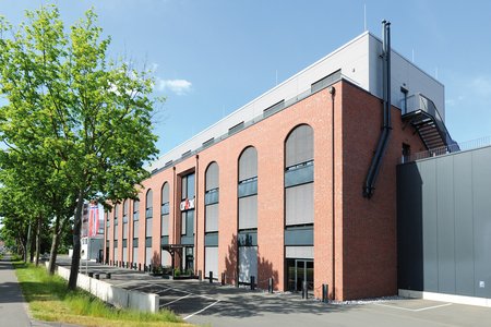 Met zijn bakstenen gevel, ronde vensterbogen en profielplaatbekleding op de bovenste verdieping doet de nieuwbouw denken aan historische industriële gebouwen.  Foto: Richard Brink GmbH & Co.