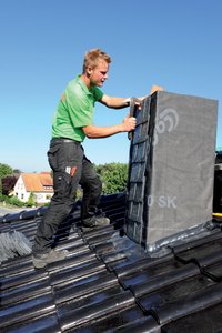 The roofers affix the roof slates to the chimney.