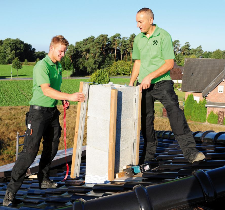 The roofers from the company Tafa Bedachungen attach the cladding suspensions to the corners of the chimney.