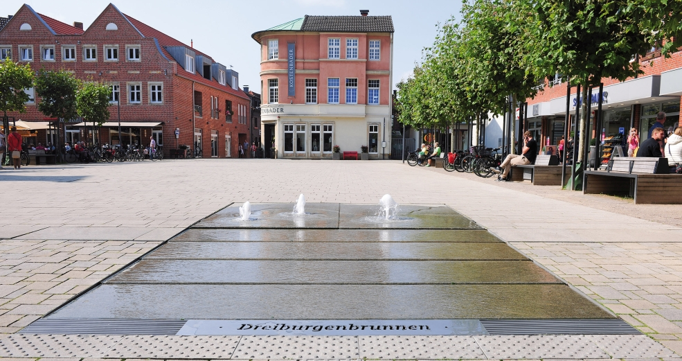 At the Marktplatz square in Lüdinghausen, a flat water feature was installed which symbolically reflects the town’s history and its popular attractions.