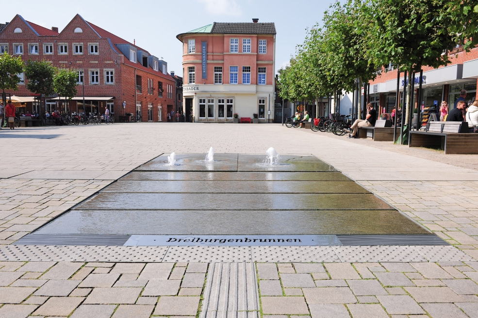 At the Marktplatz square in Lüdinghausen, a flat water feature was installed which symbolically reflects the town’s history and its popular attractions.